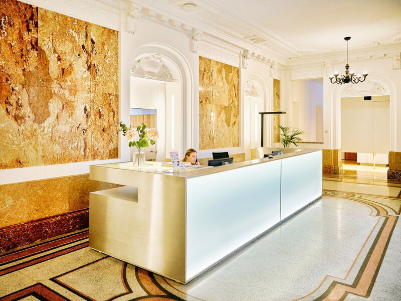 Eine moderne, beleuchtete Rezeption im historischen Innenbereich der Albert Hall mit Marmorwänden und Stuckarbeiten.