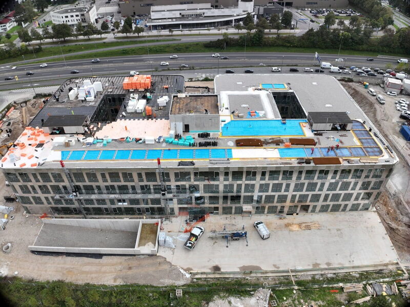 Drone shot showing the construction progress of the YOUR OFFICE Campus Noricum building with materials on the roof and surrounding infrastructure