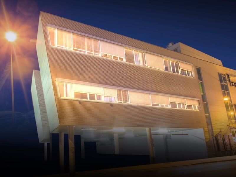 Modernes Büro- und Geschäftsgebäude mit markanter Architektur und beleuchteten Fenstern in der Dämmerung