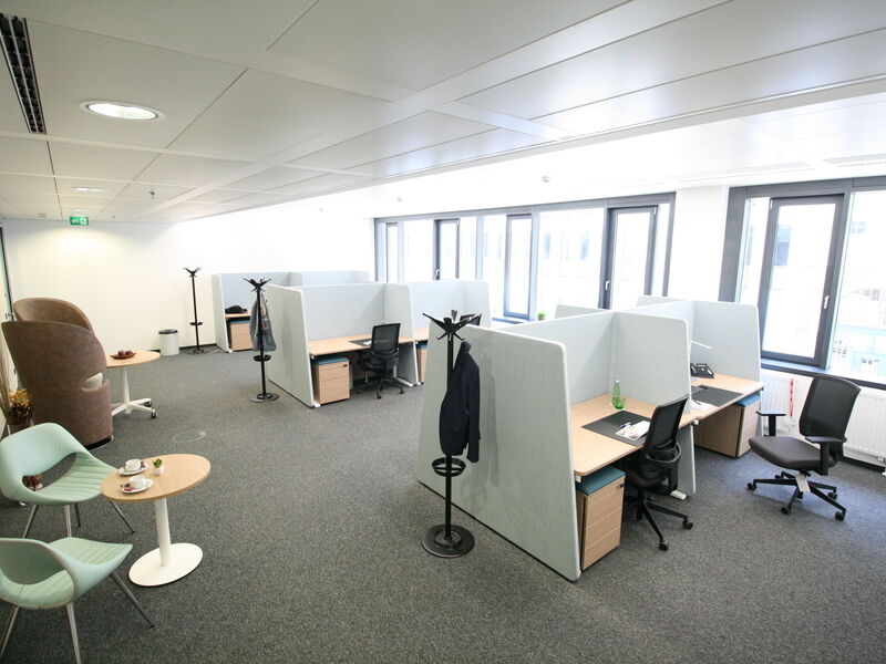 Moderne Großraumbüro-Ausstattung mit schallgedämpften Arbeitsplätzen, ergonomischen Bürostühlen und gemütlicher Sitzecke im Euro Plaza