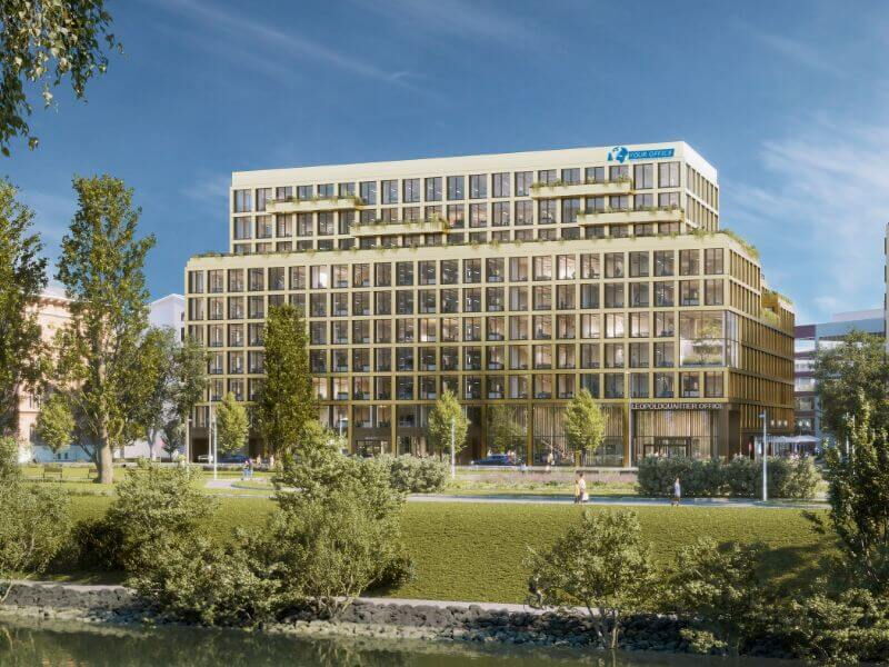 Exterior view of a modern multi-story office building with large windows and green park area in front