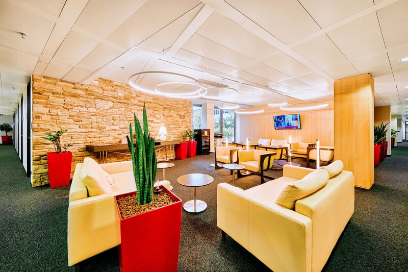 Moderne Büro-Lounge und Kommunikationszone mit gemütlichen Sitzmöbeln, stilvollen Pendelleuchten und Teeküche im EuroPlaza