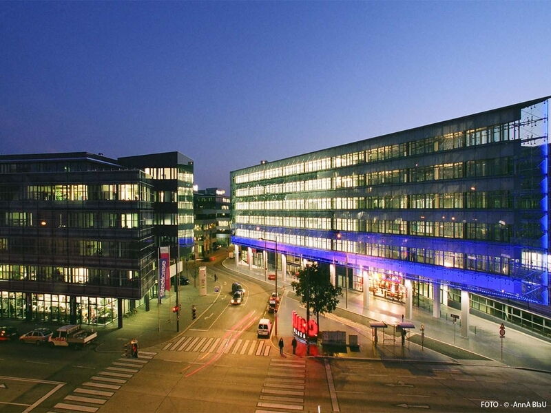 Außenansicht des beleuchteten Businessparks Euro Plaza in Wien während der Dämmerung mit modernen Bürogebäuden und Straßenverkehr.
