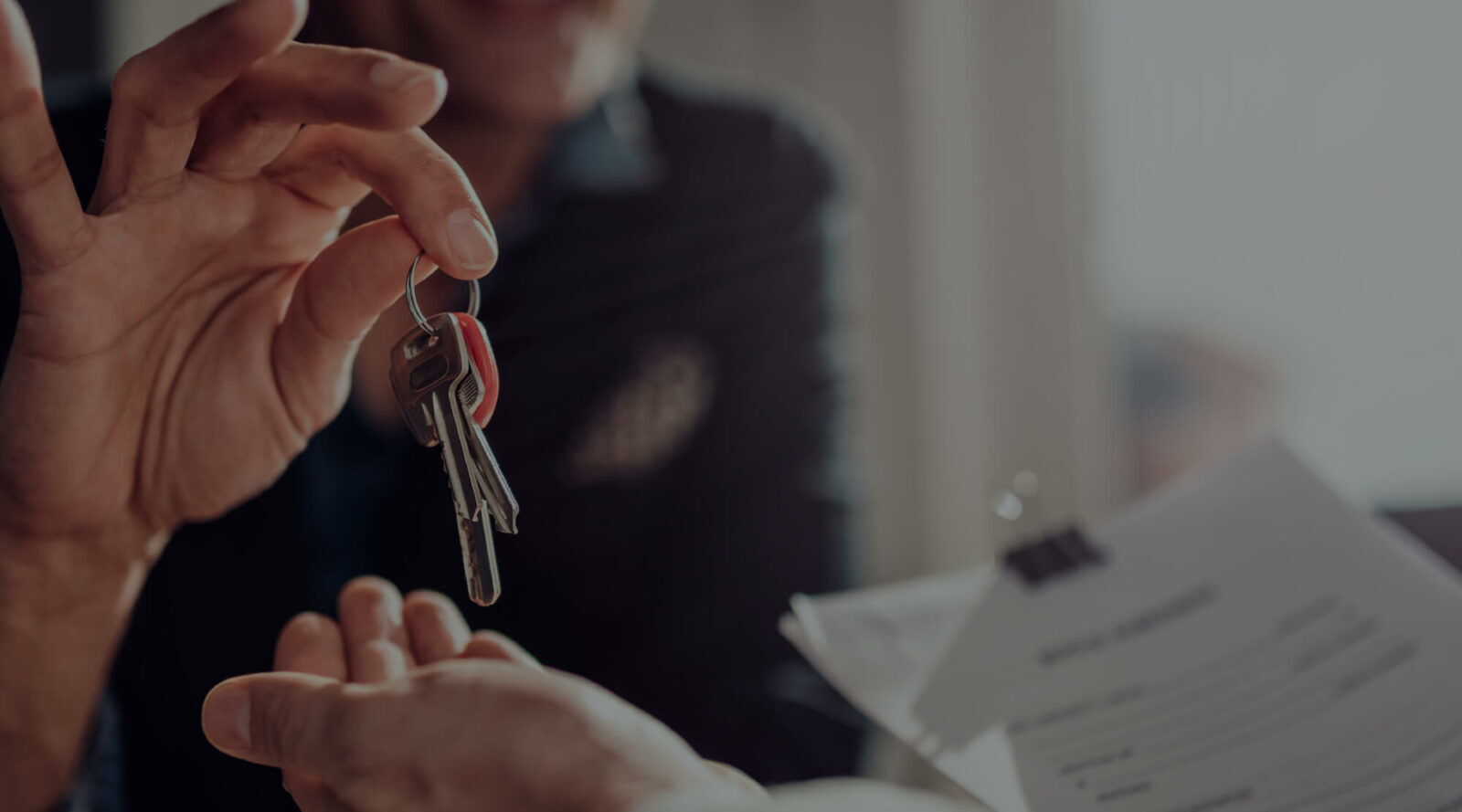 A person handing over a set of house keys to another person during a real estate transaction