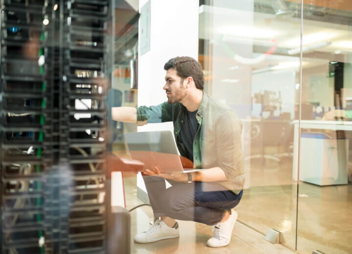 Ein IT-Techniker arbeitet mit einem Laptop vor einem Server-Rack zur Sicherung der Geschäftskontinuität