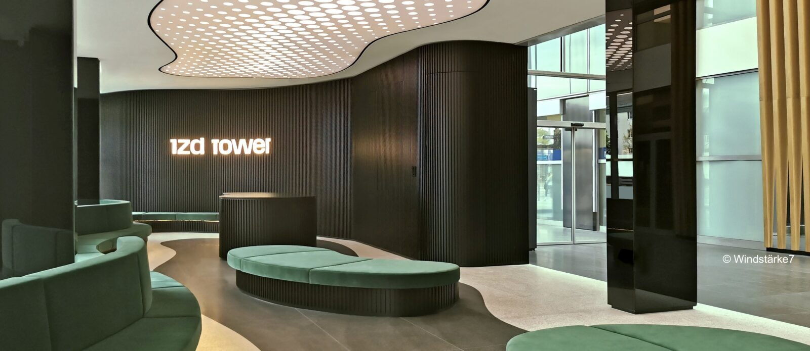 Spacious and modern lobby interior of the 1zd Tower with dark ribbed walls, green velvet seating, and a unique illuminated ceiling.