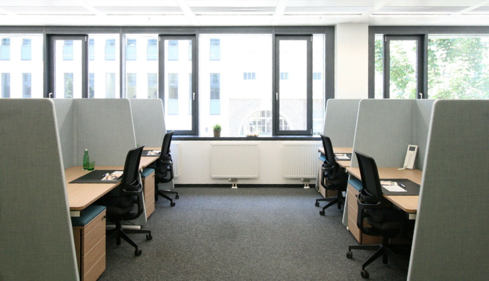Helles Großraumbüro mit ergonomischen Schreibtischen, Bürostühlen und Trennwänden für mehr Privatsphäre an den Arbeitsplätzen.