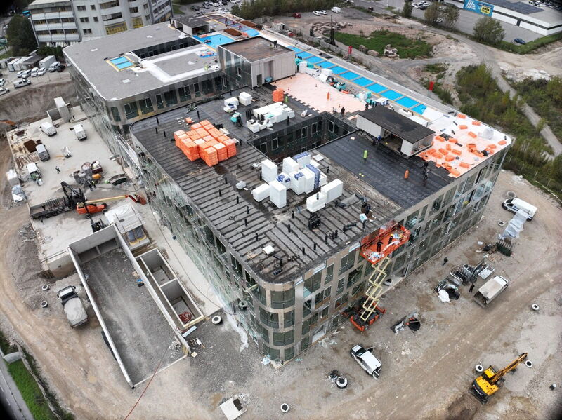 High-angle drone photo showing the construction progress of the YOUR OFFICE Campus Noricum building, featuring roof insulation and glass facade work.