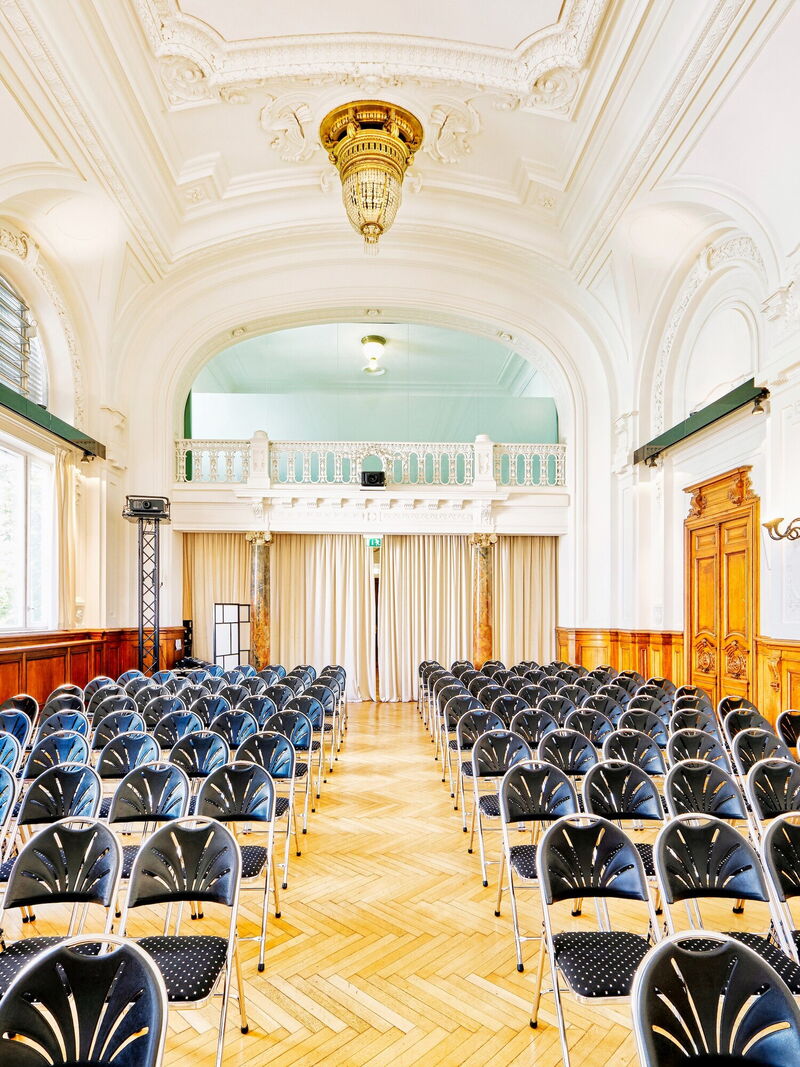 Elegantes Interieur der Albert Hall mit Stuhlreihen, prunkvoller weißer Decke und großem Kronleuchter