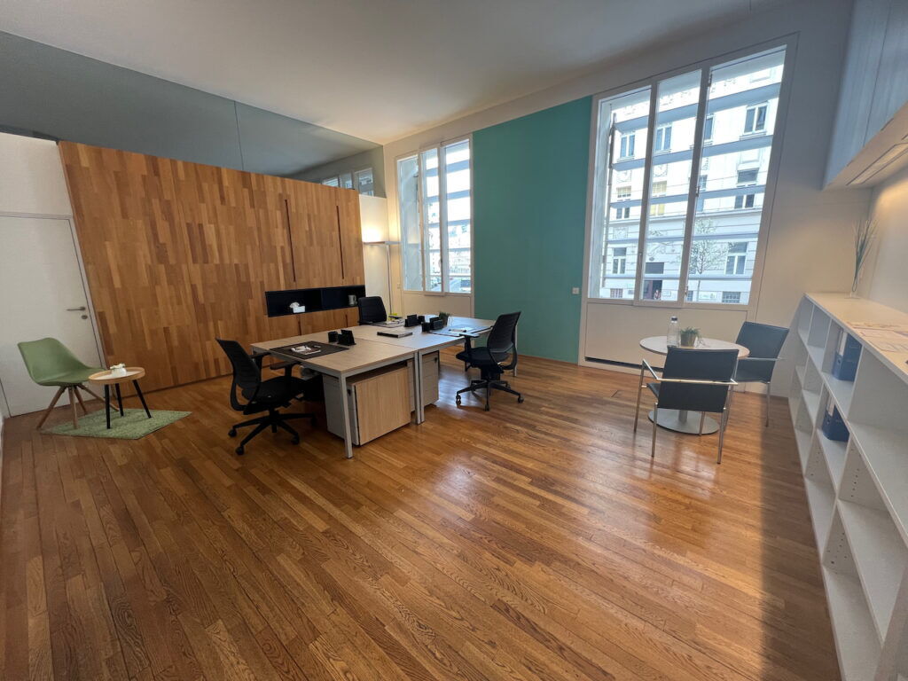 Heller und geräumiger moderner Büroraum mit Holzparkett, Schreibtischen, ergonomischen Stühlen und großen Fenstern mit Stadtblick.