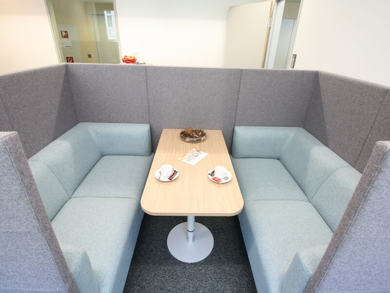 Gemütliche Akustik-Besprechungsbox mit hellblauen Sofas und Holztisch in modernem Büro im Europlaza