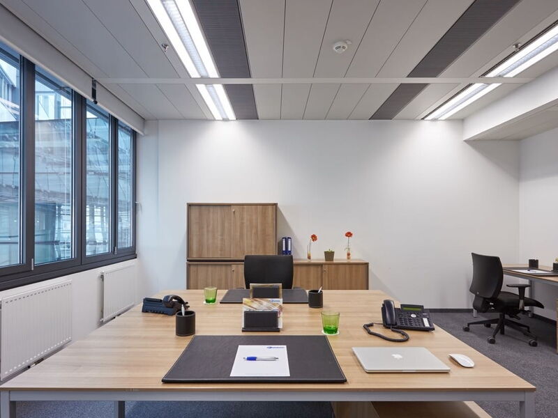 Moderne Büro-Innenausstattung mit großen Holztischen, ergonomischen Stühlen und großen Fenstern im Euro Plaza