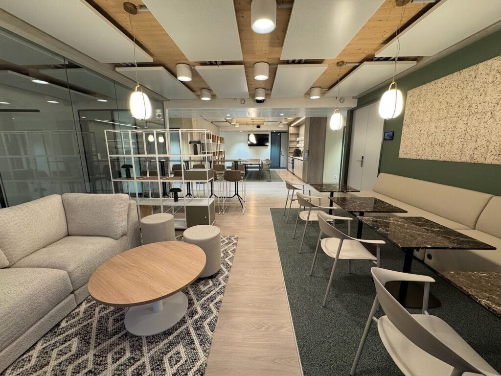 Zeitgenössischer Büro-Pausenbereich mit bequemen Sofas, Marmortischen und modernen Akustik-Deckenplatten