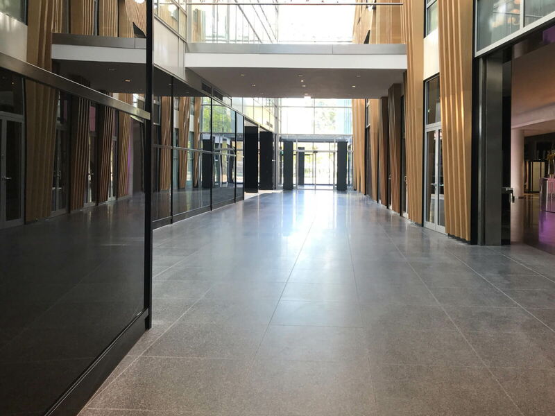 Geräumiges, modernes Bürogebäude mit einem langen polierten Flur, hölzernen Architekturelementen und Glasfassaden