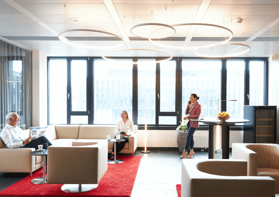 Employees working and relaxing in a modern, bright office lounge area with stylish seating and large windows