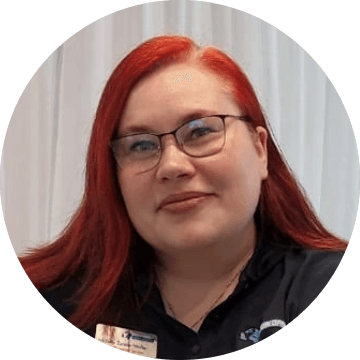 Portrait of Michelle smiling with red hair, glasses, and a name tag