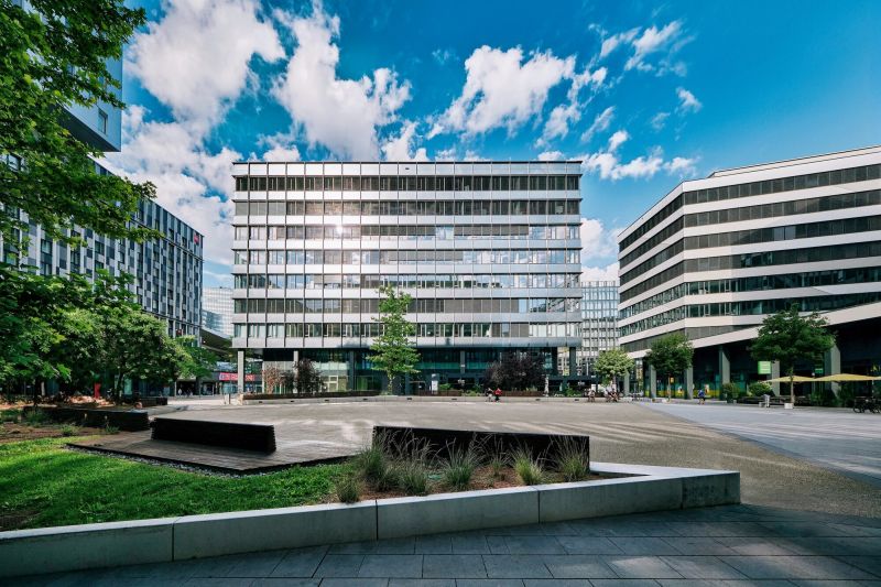 Moderne Architektur mit Bürogebäuden rund um einen öffentlichen Platz unter blauem Himmel mit Wolken in Wien