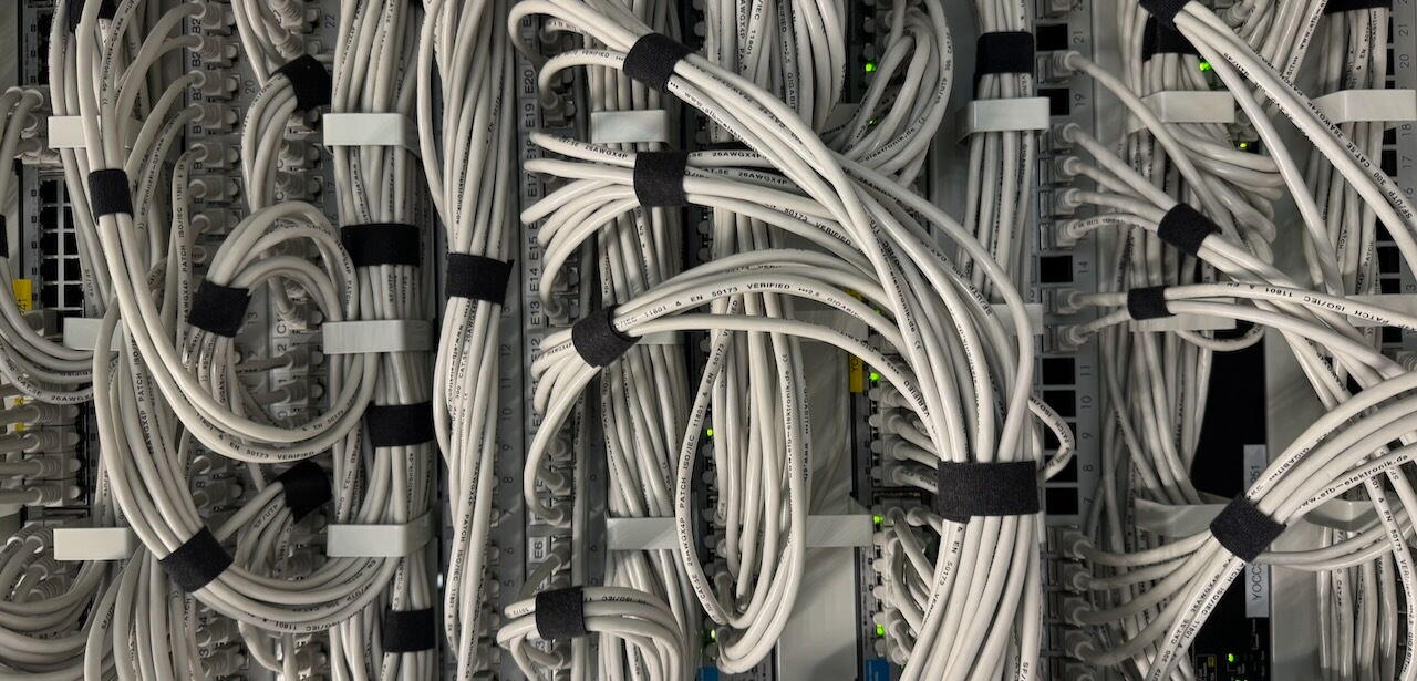 Close-up of a server rack featuring bundled white ethernet patch cables connected to network switches